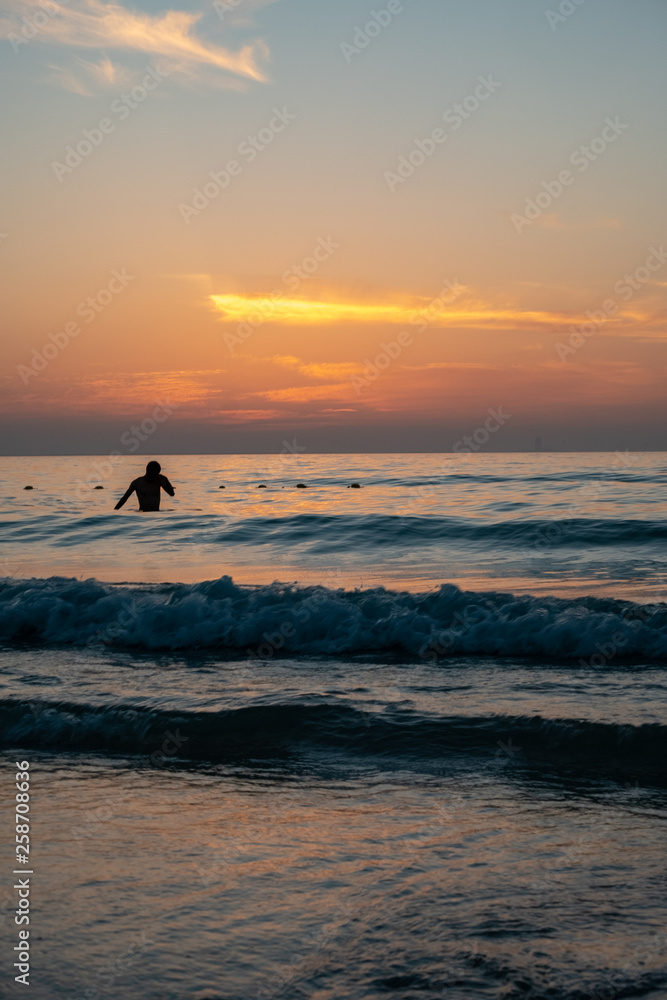 Fototapeta premium A man taking bath at beach during sunset