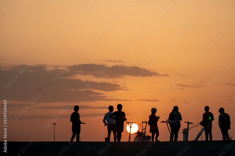 Silhouette of teenagers with their E-bikes during sunset