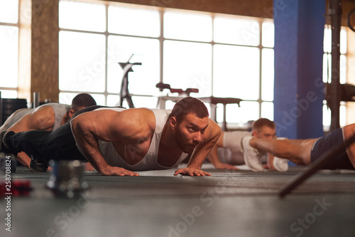 Small Group of Muscular Male Adults Warming Up Training Push Ups.