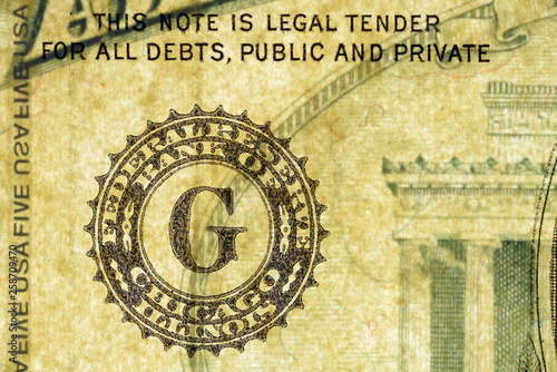 Close-up at Federal Reserve Bank of Chicago text, highly magnified surface of used 5 dollars note with visible details of cotton fiber paper, with all flaws, watermarks and traces of usage.
