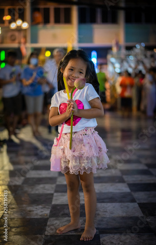 little girl hold the candle and lotus in hand for Buddhist ceremony around temple at night photo