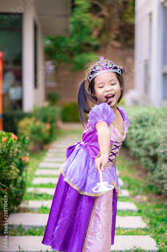 Portrait of cute smiling little girl in princess costume standing on the footpath