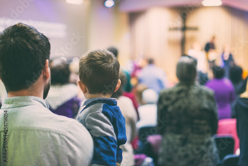 Father with his son participate at christian congregation worship photo