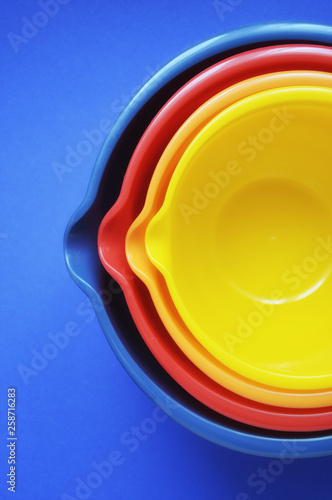 colored kitchen bowls on blue background