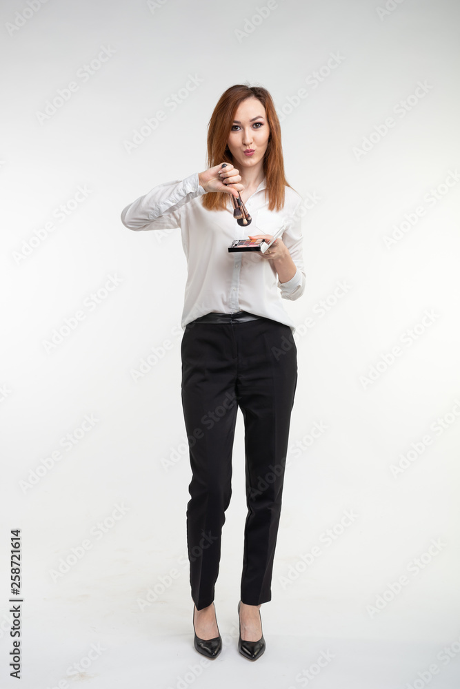 Attractive visagist or korean make-up artist holding a makeup brushes and a palette of eye shadow on white background Attractive visagist or korean make-up artist holding a makeup brushes and a palette of eye shadow on white background