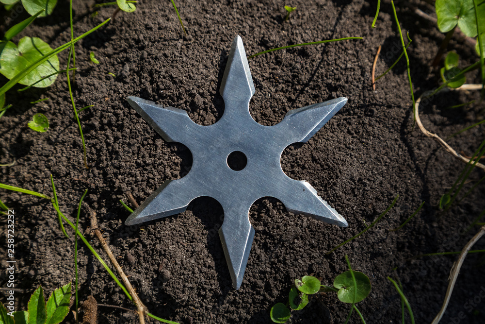 Shuriken (throwing star), traditional japanese ninja cold weapon stuck in wooden background