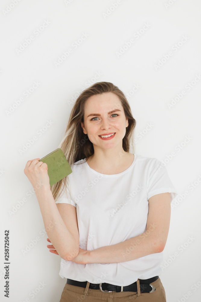 Portrait of succesful smiling woman in casual wear with green book on light background. Portrait of succesful smiling woman in casual wear with green book on light background.