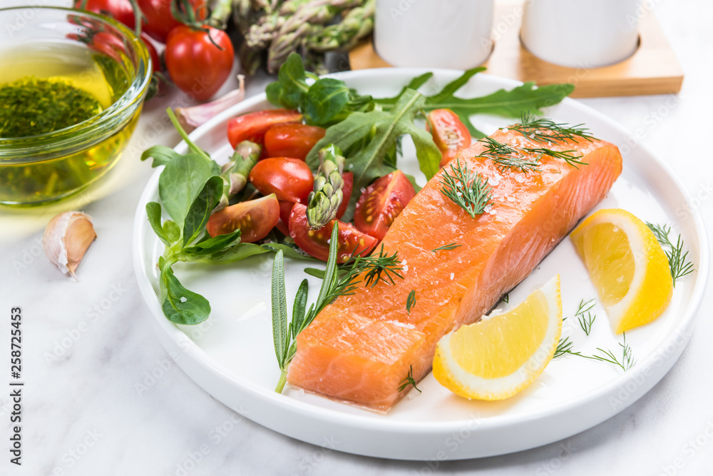 Fresh salmon pieces with salad,herbs and lemon on plate Fresh salmon pieces with salad,herbs and lemon on plate