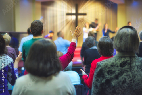 Christian congregation worship God together, with cross with light rays in background