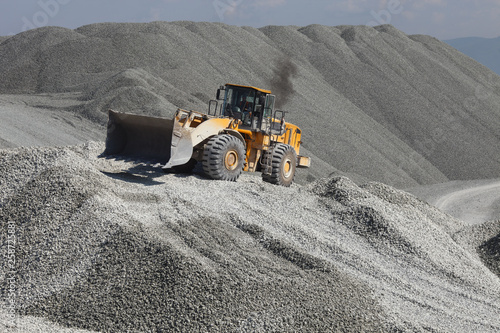 Heavy wheel loader excavator against the background of gravel hills. Quarry equipment. Mining industry. photo