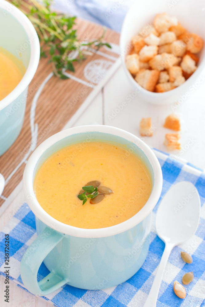 Pumpkin soup in a blue enameled mug, selective focus Pumpkin soup in a blue enameled mug, selective focus