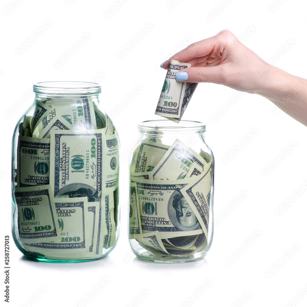 Money dollars bank notes in glass jar, hand put money isolated on white background, concept save money Money dollars bank notes in glass jar, hand put money isolated on white background, concept save money