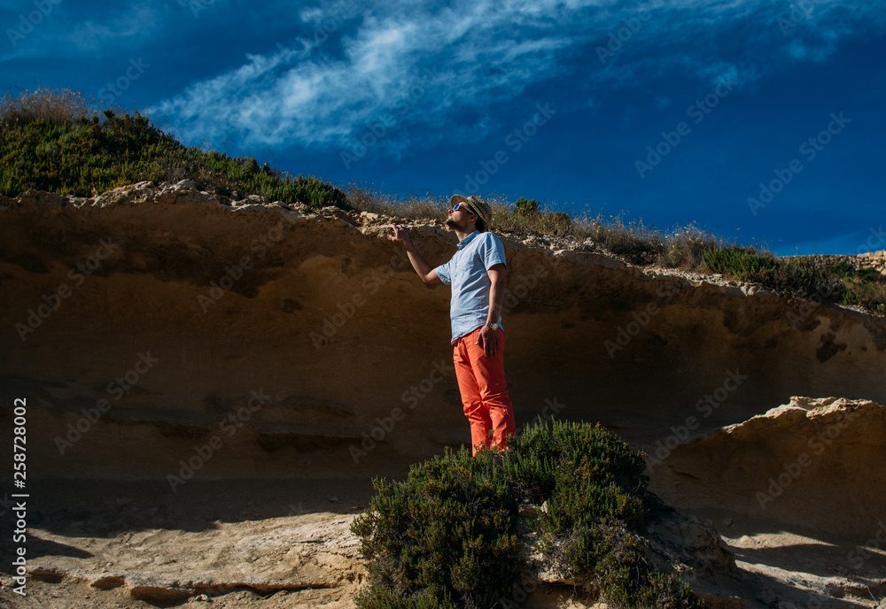 Obraz premium Man in sunglasses and red trousers staying in the hills