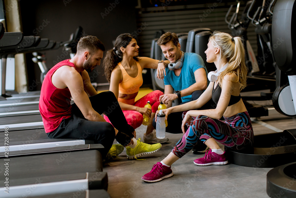Friends in sportswear talking and laughing together while resting in the gym after a workout Friends in sportswear talking and laughing together while resting in the gym after a workout