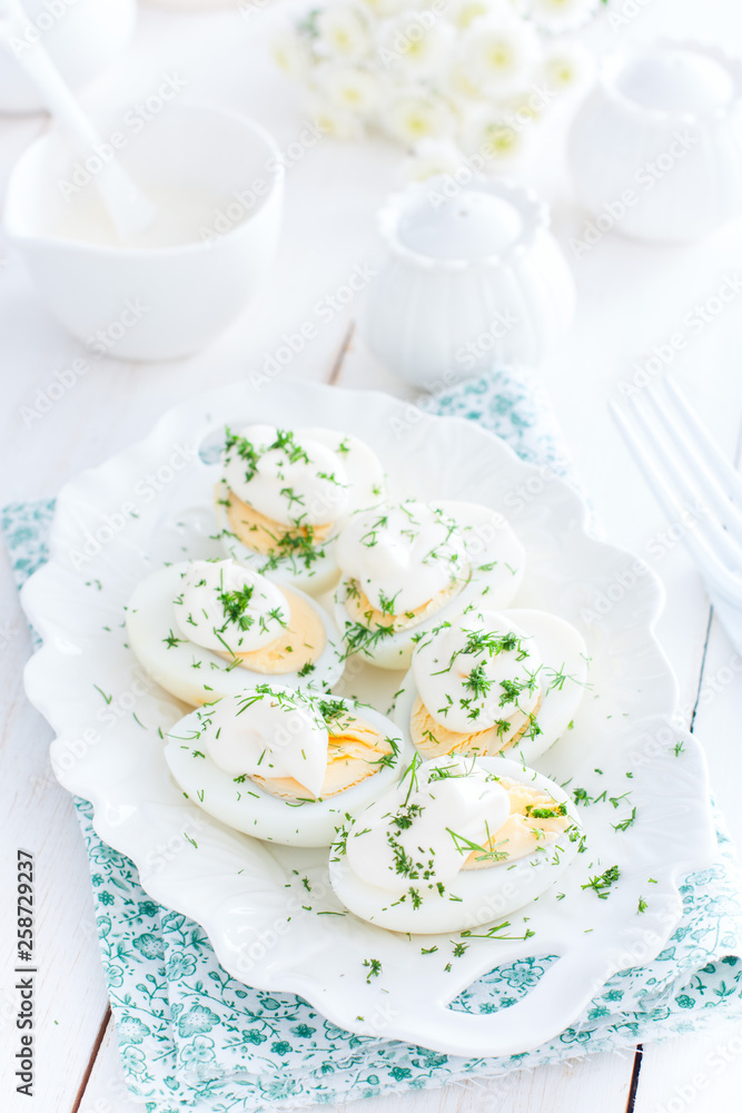 Snack of eggs under mayonnaise on a white plate, selective focus