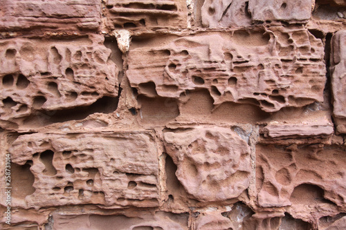 Close up image of old textured sandstone brickwork worn by the wind on an English castle