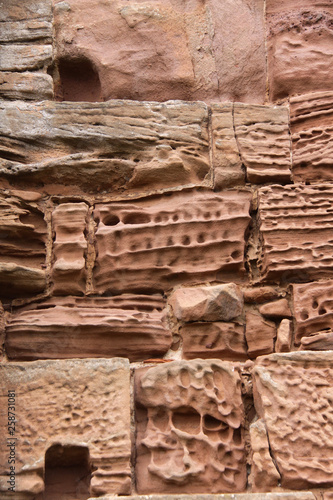 Close up image of old textured sandstone brickwork worn by the wind on an English castle