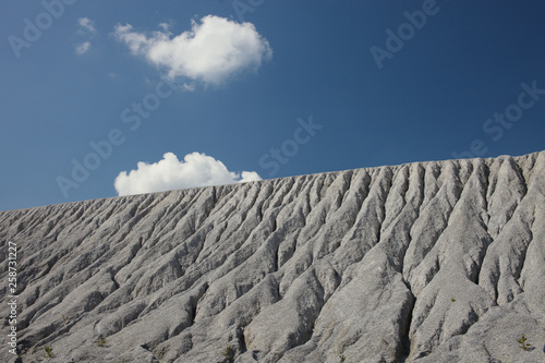 Slope of an abandoned slagheap covered ravines against the blue sky. Mining industry. photo