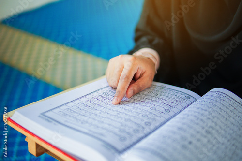 Close up view of muslim woman reading the holy Al Quran inside a mosque photo
