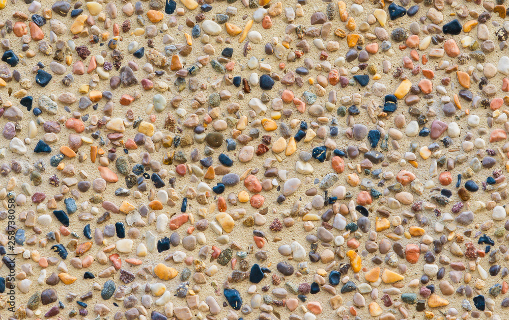 Concrete wall with colorful stones and gravel as background