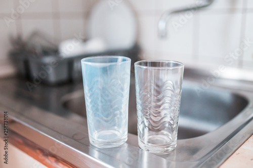 Dirty and clean glass cups on a kitchen sink. Broken washing machine concept.