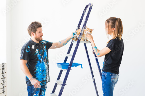 People, pet, renovation and repair concept - Portrait of lovely couple with cat doing redecoration in apartment