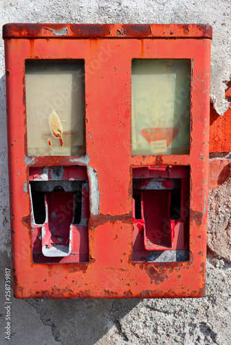 old neglected gumball machine on a rundown house wall