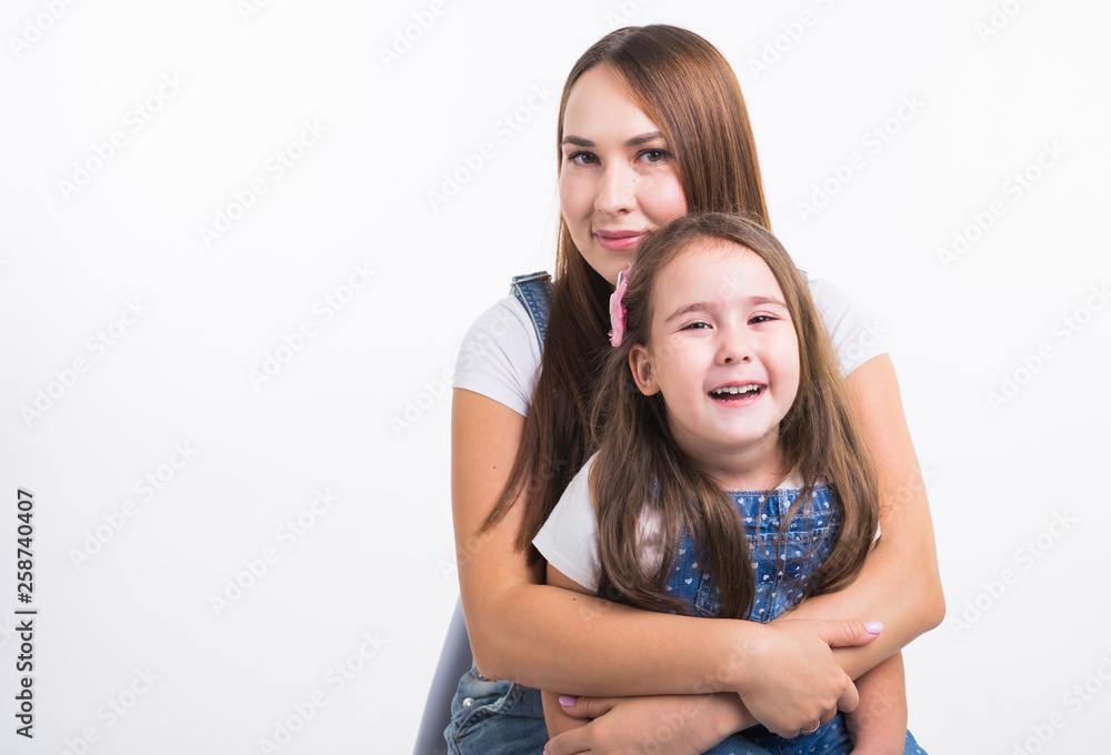 Motherhood, family and relationship concept - Happy mother and little daughter having fun on white background Motherhood, family and relationship concept - Happy mother and little daughter having fun on white background