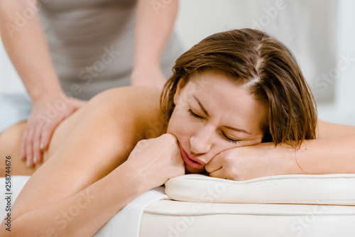 Relaxed woman sleeping while having back massage procedure