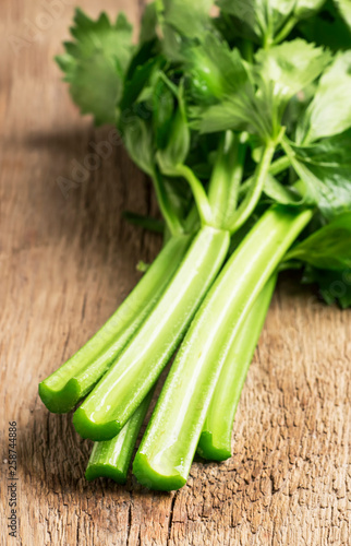 Stems of fresh celery with leaves on the table, vintage wooden kitchen table background, selective focus