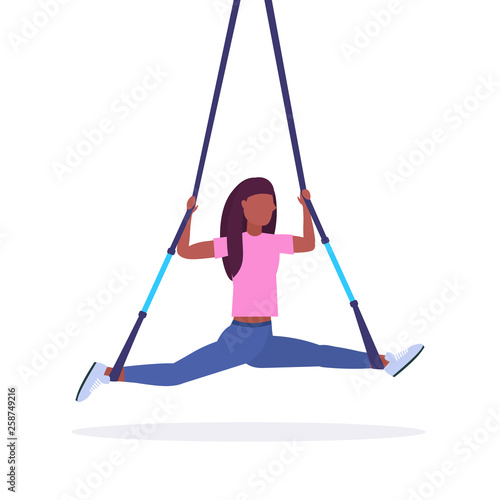 sporty woman doing splits exercises with suspension fitness straps elastic rope african american girl training in gym crossfit cardio workout concept flat white background full length