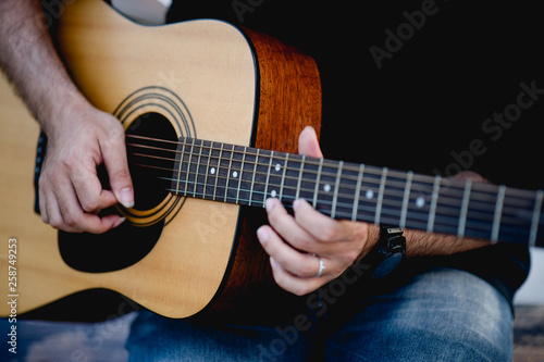 Picture of a guitarist, a young man playing a guitar while sitting in a natural garden,music concept