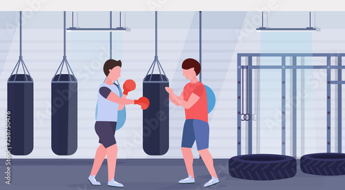man boxer with personal trainer hitting punching bag in red boxing gloves guy fighter training workout modern fight club gym interior healthy lifestyle concept flat horizontal