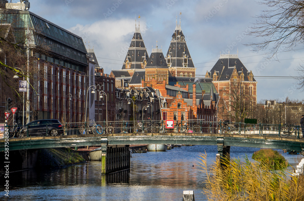 One of Amsterdam museum from long distance with reflection in canal and bridge on foreground 