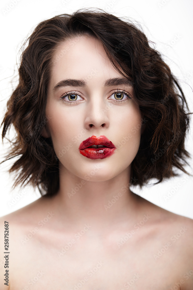 Fototapeta premium Portrait of female face. Human woman half-face with unusual beauty makeup. Girl with perfect skin, green pistachio colour eyes and scarlet red lips make-up.