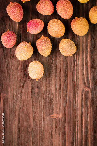 Fresh organic lychee fruits on brown wooden background.