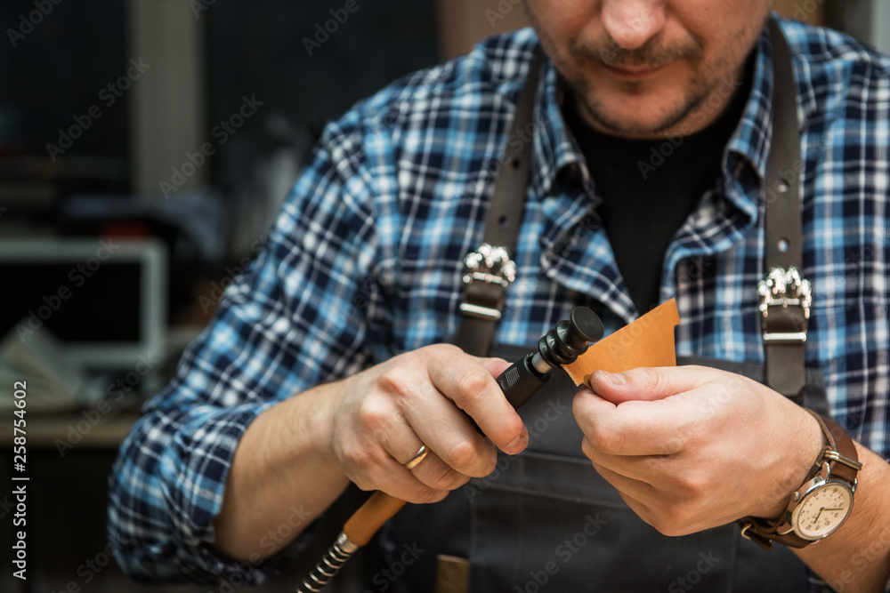 Fototapeta premium Man working with leather textile at a workshop.