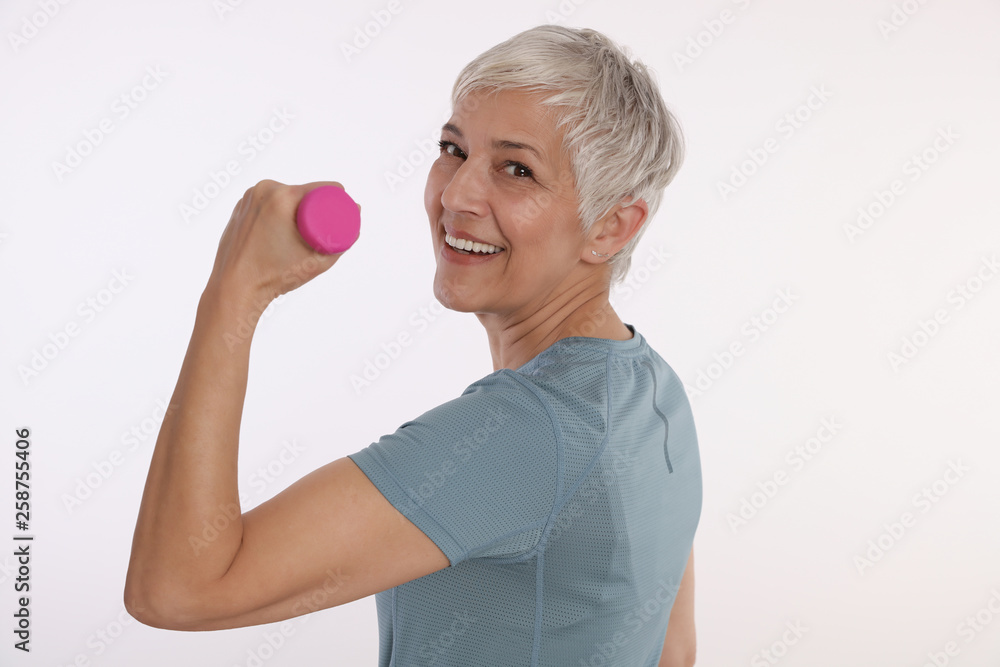Smiling Mature Woman in sport outfit holding dumbbells isolated on white backround. Active senior lifestyle Smiling Mature Woman in sport outfit holding dumbbells isolated on white backround. Active senior lifestyle