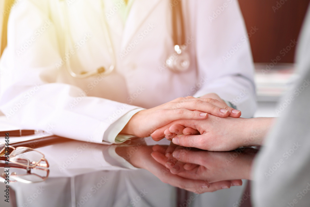 Doctor and  female patient sitting at the desk and talking  in clinic near window. Medicine and health care concept. Green is main color
