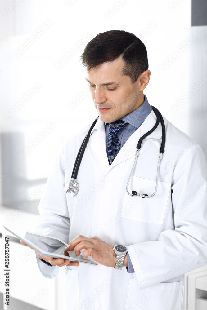 Doctor man using tablet computer for network research or virtual disease treatment. Perfect medical service in clinic. Happy future for modern medicine, medic data and healthcare concepts Doctor man using tablet computer for network research or virtual disease treatment. Perfect medical service in clinic. Happy future for modern medicine, medic data and healthcare concepts