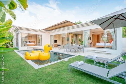 home or house Exterior design showing tropical pool villa with greenery garden, sun bed and floating duck © Stock PK