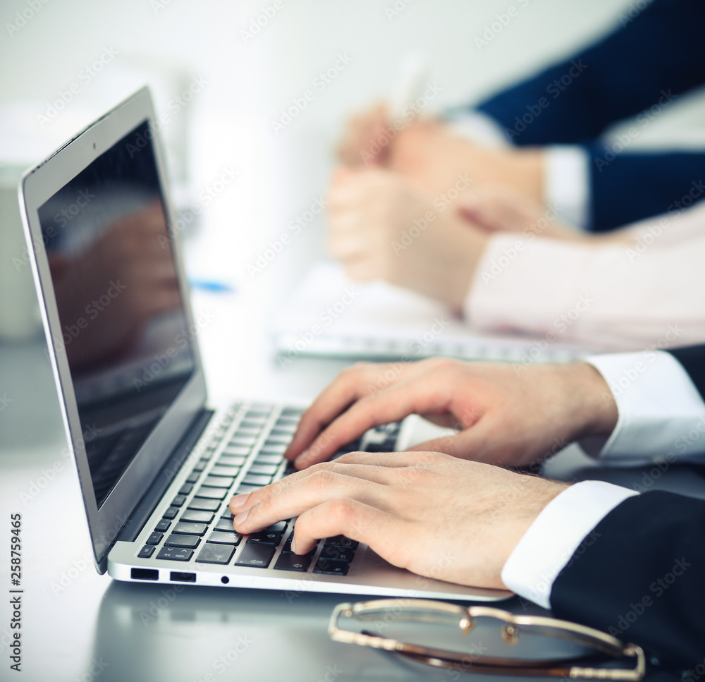 Group of business people working together in office. Man hands typing on laptop computer Group of business people working together in office. Man hands typing on laptop computer