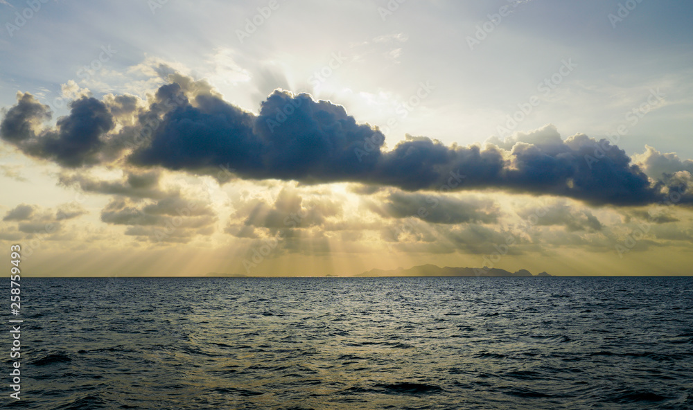 sun rays pass through clouds over sea