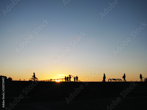 Silhouettes of people against the backdrop of the sunset and the evening sky.