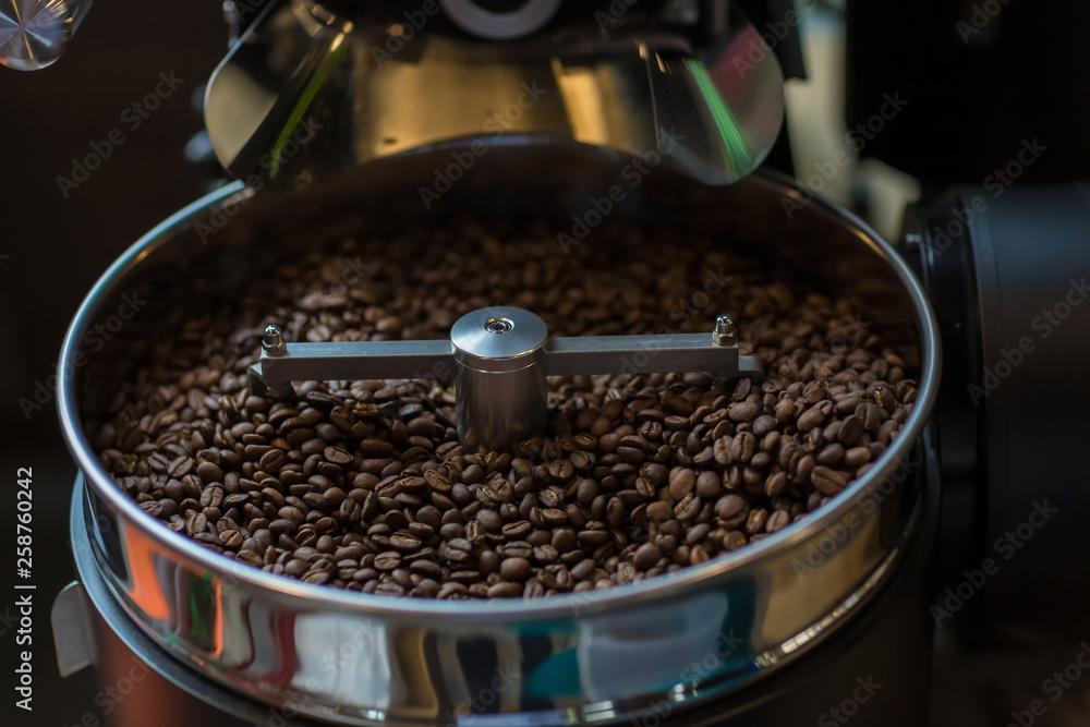 Freshly roasted aromatic coffee beans in a modern coffee roasting machine. Fresh Coffee Beans - Freshly roasted spinning cooler professional machine. Mixing roasted coffee.