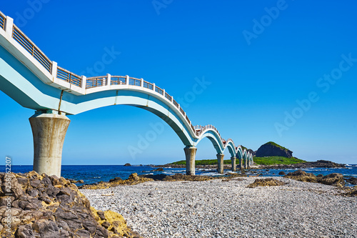 Beautiful scenic of Sanxiantai arch bridge with blue ocean with Three saint island in behind at Chenggong district in Taitung city, Taiwan. photo