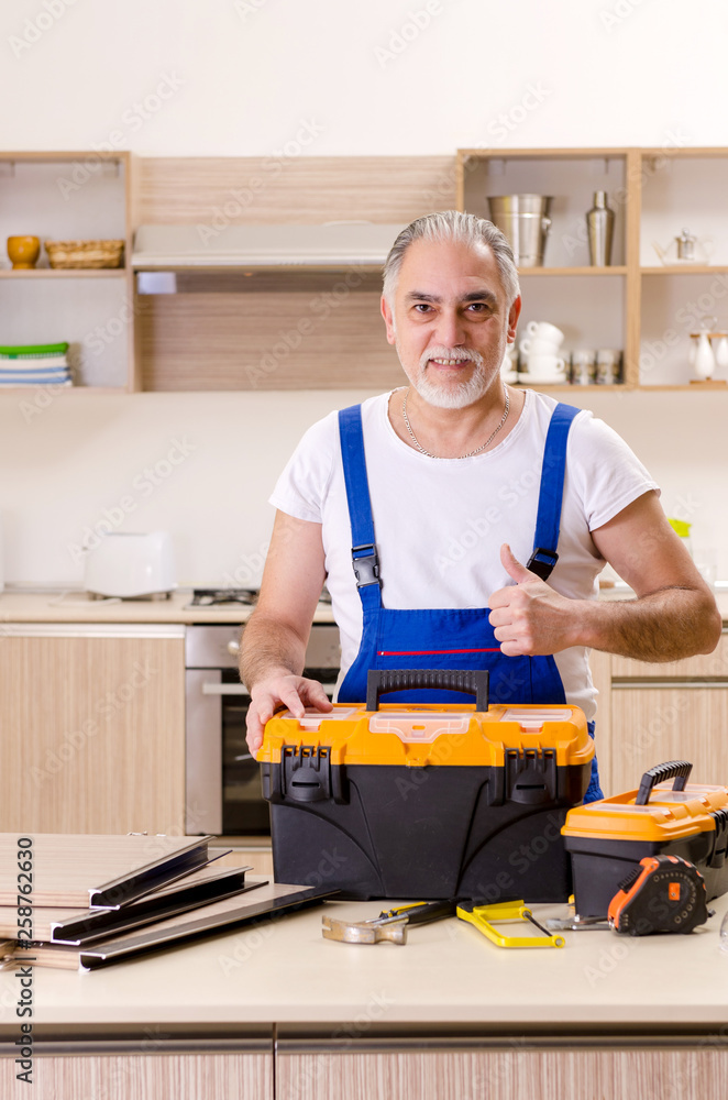 Aged contractor repairman working in the kitchen Aged contractor repairman working in the kitchen