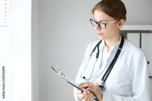 Doctor woman at work. Portrait of female physician using clipboard at hospital office. Medicine and healthcare concept