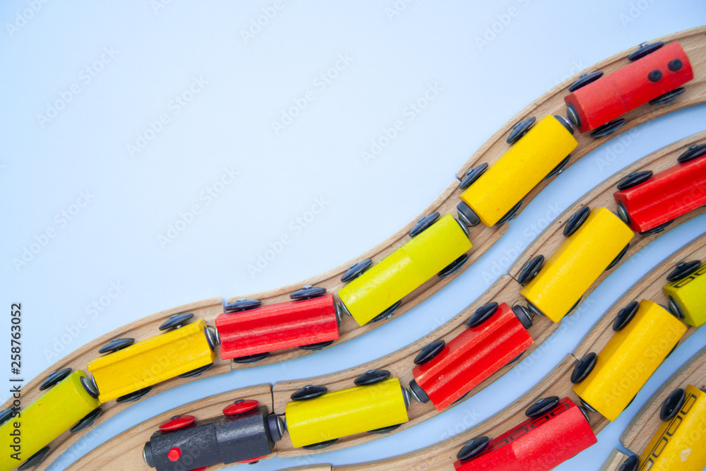 frame for text made of multicolor kids train cars bricks on wooden railway on blue background. Copyspase. top view. flat lay. Children toys on the table.