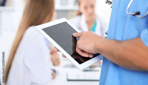 Surgeon doctor using tablet computer, close-up of hands at touch pad screen